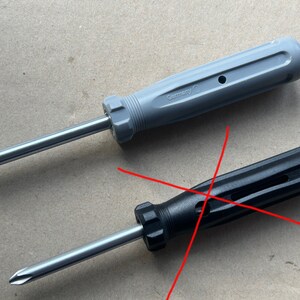 May include: Two screwdrivers with different colored handles. The top screwdriver has a gray handle with the word "Germany" printed on it. The bottom screwdriver has a black handle.