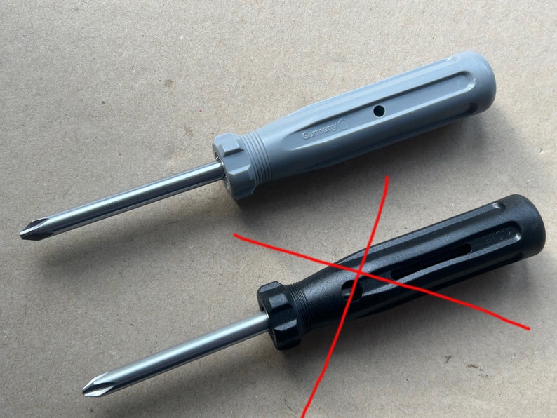 May include: Two screwdrivers with different colored handles. The top screwdriver has a gray handle with the word "Germany" printed on it. The bottom screwdriver has a black handle.