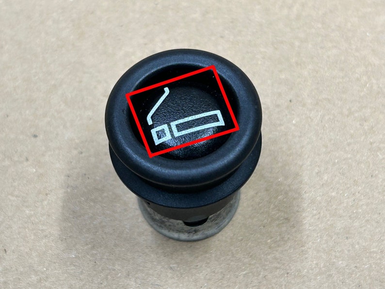 May include: Black cigarette lighter socket with a white no smoking symbol.