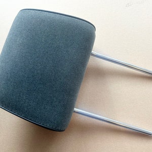 May include: Gray fabric headrest with adjustable metal rods. The headrest is designed to provide support and comfort for the head and neck.