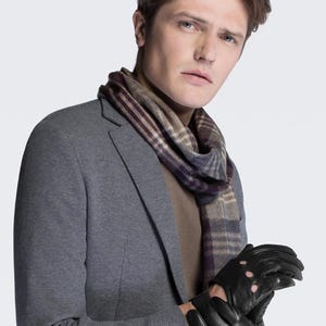 May include: A man wearing a gray blazer with a brown and purple plaid scarf and black leather gloves with pink accents.