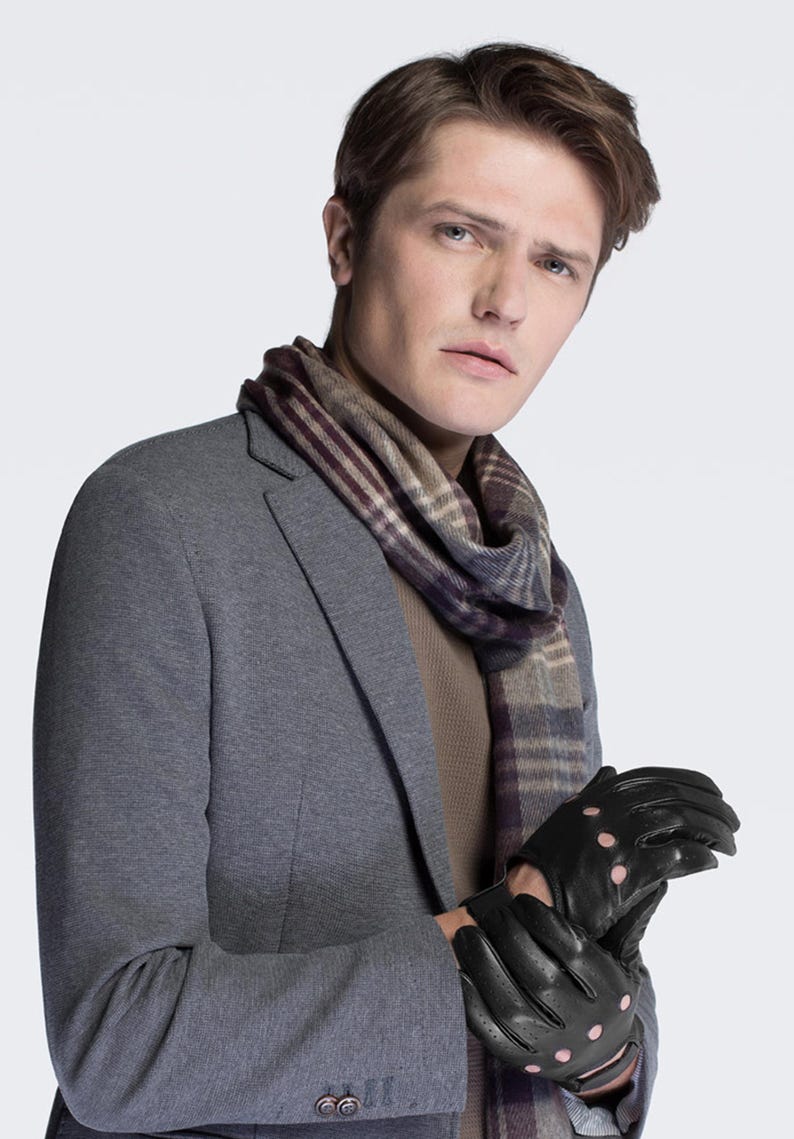 May include: A man wearing a gray blazer with a brown and purple plaid scarf and black leather gloves with pink accents.