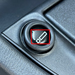 May include: A black plastic car cigarette lighter with a white cigarette symbol.