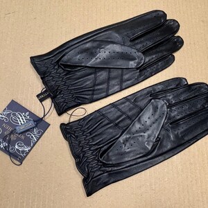 May include: A pair of black leather driving gloves with a textured surface and a small tag that says "The Collection".
