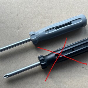 May include: Two screwdrivers, one with a gray handle and the other with a black handle. The gray screwdriver has the text "HEYCO" on the handle. Both screwdrivers have a silver metal shaft.
