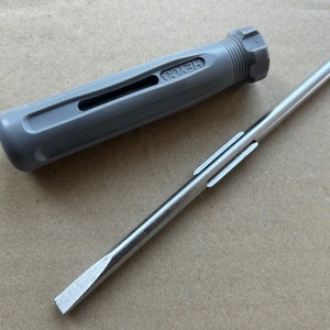 May include: A gray screwdriver with a black handle and the word "HEXOO" printed on it. The screwdriver has a flat head and a metal shaft.