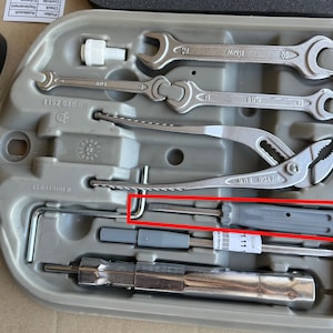 May include: A gray plastic tool kit with a variety of tools, including wrenches, pliers, and a screwdriver. The kit is labeled "BMW" and "ELDATALHER".