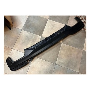 Könnte beinhalten: Schwarzer Kunststoff-Heckdiffusor für ein Auto. Der Diffusor hat ein Wabenmuster und ist so konzipiert, dass er die Aerodynamik verbessert.