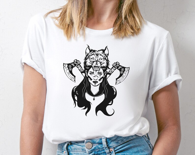 Peut inclure: T-shirt blanc avec un motif noir et blanc d'une femme avec une t&ecirc;te de loup et deux haches.