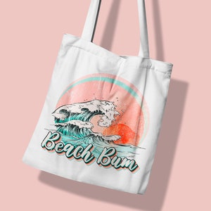 May include: White tote bag featuring a retro design with ocean waves, a setting sun, and the text "Beach Bum" in a teal and orange font. The bag has two white handles.