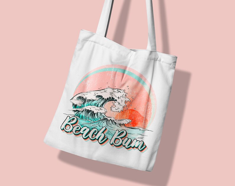 May include: White tote bag featuring a retro design with ocean waves, a setting sun, and the text "Beach Bum" in a teal and orange font. The bag has two white handles.