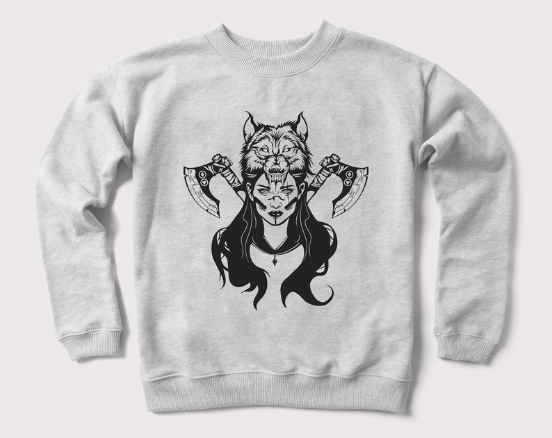 Peut inclure: Un sweat-shirt gris avec un imprim&eacute; graphique noir et blanc d'une femme avec une t&ecirc;te de loup et deux haches.