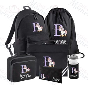 Op de afbeelding: Zwarte schoolset met rugzak, gymtas, lunchbox, etui en drinkfles. Elk item heeft een paarse "B" met een eenhoorn en de naam "Bonnie". Perfect voor school.