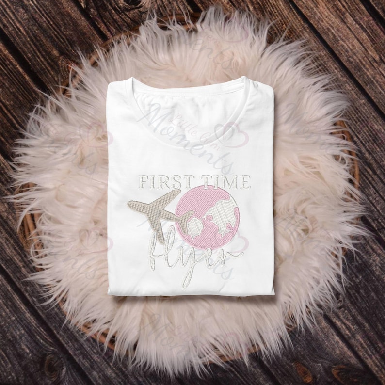 May include: White t-shirt with the text "First Time Flyers" and an embroidered airplane and globe. The globe is pink and the airplane is beige.