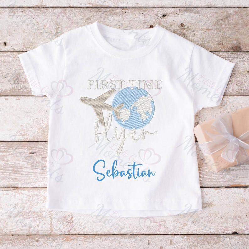 May include: White t-shirt with a blue globe and airplane graphic. The text "My First Time Flying" and the name "Sebastian" are embroidered on the shirt.