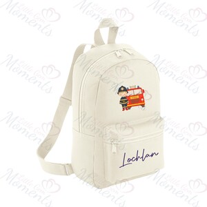 May include: Off-white backpack featuring a firefighter and fire truck graphic. The backpack has a front pocket with a zipper and the name "Lochlan" in cursive script. The bag has adjustable straps and a top handle.