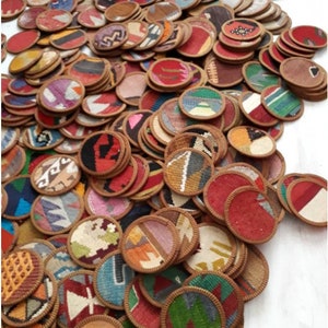 May include: A large collection of circular coasters featuring a variety of woven textile patterns in diverse colors including red, blue, green, yellow, and brown. Each coaster is finished with a stitched brown fabric border around the edge.