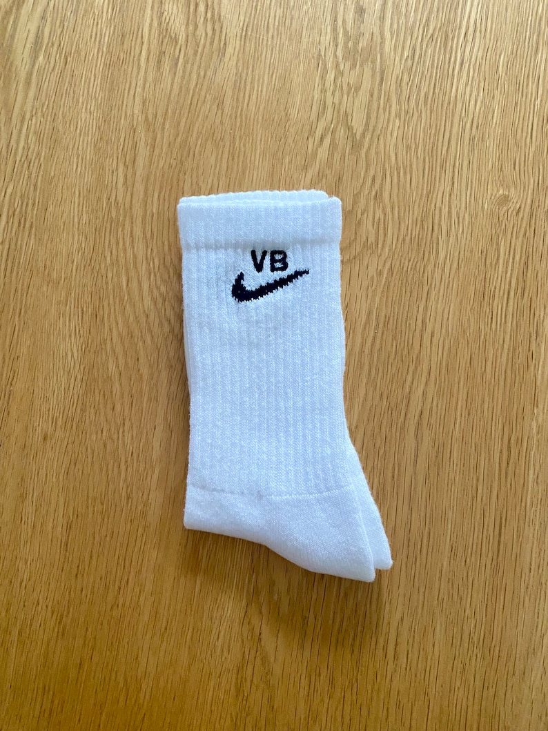 May include: White cotton socks with a black Nike swoosh and the letters "VB" embroidered on the top.