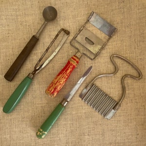 May include: A set of five vintage kitchen tools, including a melon baller, a grater, a knife, a zester, and a small handheld slicer. The tools are made of metal and have wooden handles.