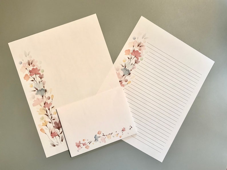 May include: Stationery set featuring a floral design in soft pastel colors. The set includes a lined writing sheet, a blank sheet, and an envelope. The floral design is on the corner of each piece, adding a delicate touch.