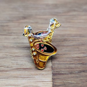 Duelling saxophone enamel pin badge.