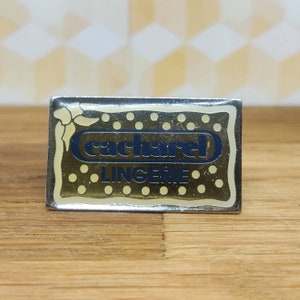 Cacharel lingerie french fashion pin badge. Hat Tie Lapel bag scarf denim leather jacket. Vintage retro collectable advertising gift.