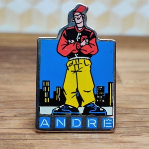 Andre french fashion pin badge. Hat Tie Lapel bag denim or leather jacket. Vintage retro collectable advertising collectable gift.