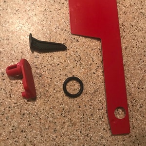 May include: A red metal mailbox with a black plastic flag and a black rubber O-ring. There are two red plastic pieces, one with a small hole and the other with a small tab.