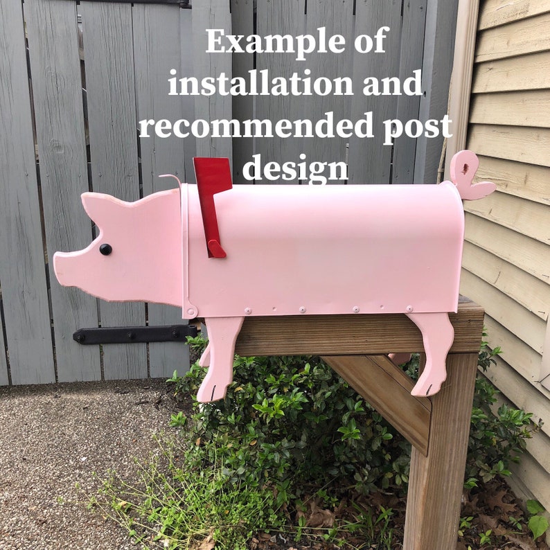 Puede incluir: Buz&oacute;n de correo en forma de cerdo rosa con una bandera roja, montado en un poste de madera. Ejemplo de instalaci&oacute;n y dise&ntilde;o de poste recomendado.