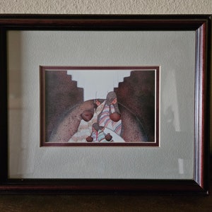 May include: Framed watercolour painting of Native American women carrying clay pots in a brown and white adobe building.