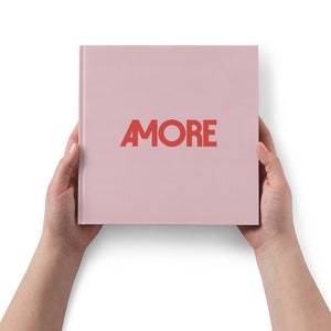Könnte beinhalten: Ein pinkfarbenes Hardcover-Buch mit dem Wort "AMORE" in Rot auf dem Einband.
