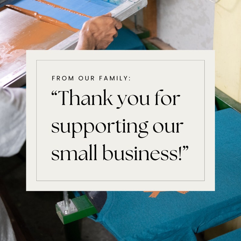 May include: A person is using a screen printing press to print a design onto a blue t-shirt. The design is a small, orange graphic. The text on the white rectangle reads "From our family: "Thank you for supporting our small business!"