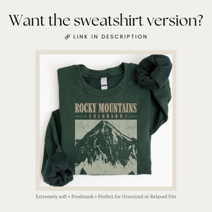 May include: A dark green sweatshirt with the text "ROCKY MOUNTAINS &bull; COLORADO &bull;" and a graphic of a mountain range. The sweatshirt is folded and has a relaxed fit.