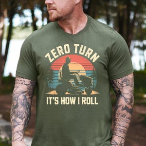 May include: A green t-shirt with a retro-style graphic of a person riding a zero turn lawnmower. The text "Zero Turn It's How I Roll" is printed on the shirt.