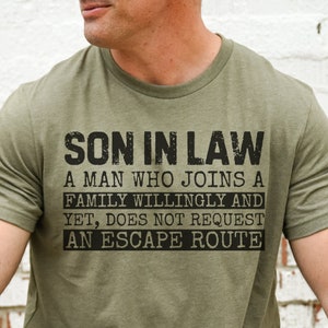 May include: A green t-shirt with the text "Son in Law. A man who joins a family willingly and yet, does not request an escape route."