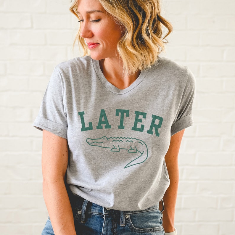May include: A gray t-shirt with a green alligator graphic and the text "LATER" in a collegiate font.