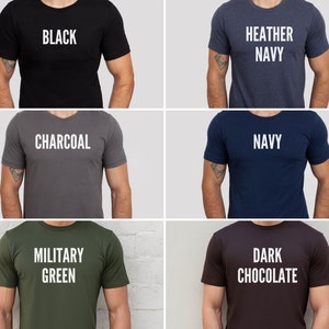May include: A collection of six short-sleeved t-shirts in various colors: black, heather navy, charcoal, navy, military green, and dark chocolate. Each shirt displays its color name in bold, white capital letters.
