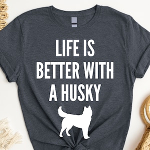 May include: A dark gray t-shirt with white text that reads "Life is better with a husky". A white silhouette of a husky is below the text.