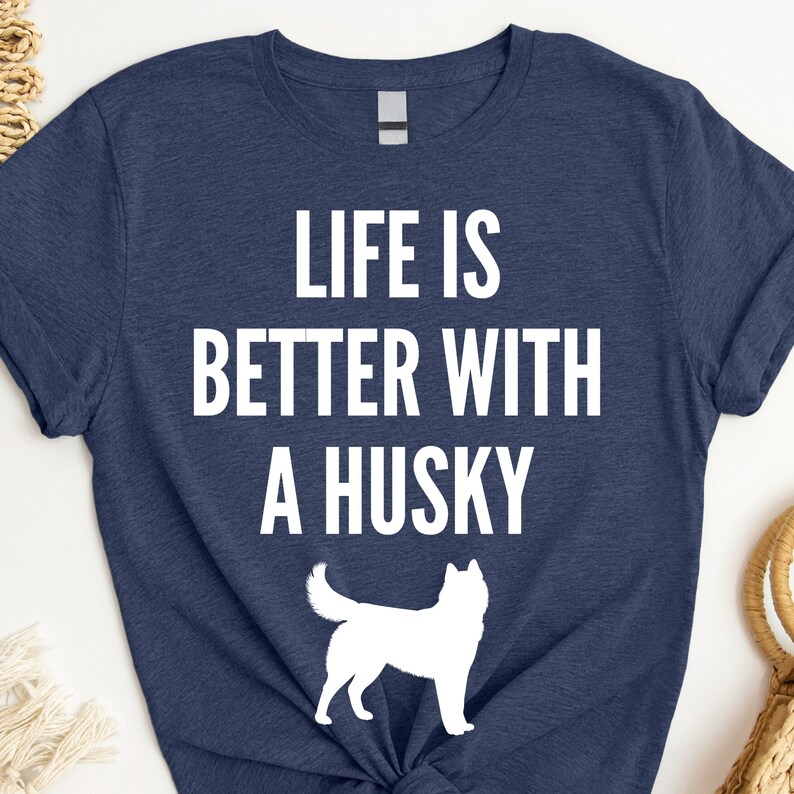 May include: A navy blue t-shirt with white text that reads "Life is better with a husky". A white silhouette of a husky is below the text.