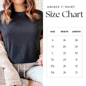May include: A dark gray unisex t-shirt with a size chart. The size chart lists sizes S through 3XL, with corresponding width and length measurements in inches. The shirt is displayed on a person wearing a cream-colored cardigan and gray sweatpants.