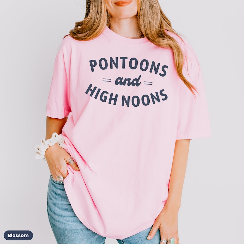Pode incluir: Uma camiseta rosa com o texto "Pontoons = and = High Noons" em azul marinho.