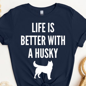 May include: A navy blue t-shirt with white text that reads "Life is better with a husky". A white silhouette of a husky is below the text.