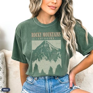 May include: A green t-shirt with a vintage-style graphic of a mountain range and the text "Rocky Mountains Colorado".