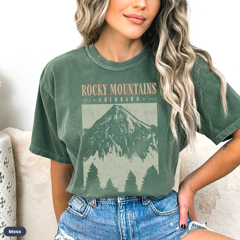 May include: A green t-shirt with a vintage-style graphic of a mountain range and the text "Rocky Mountains Colorado".