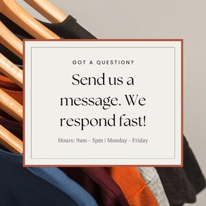 May include: A white rectangle with a brown border contains text that reads "GOT A QUESTION? Send us a message. We respond fast! Hours: 9am - 5pm | Monday - Friday". The rectangle is in front of a stack of colorful t-shirts hanging on wooden hangers.