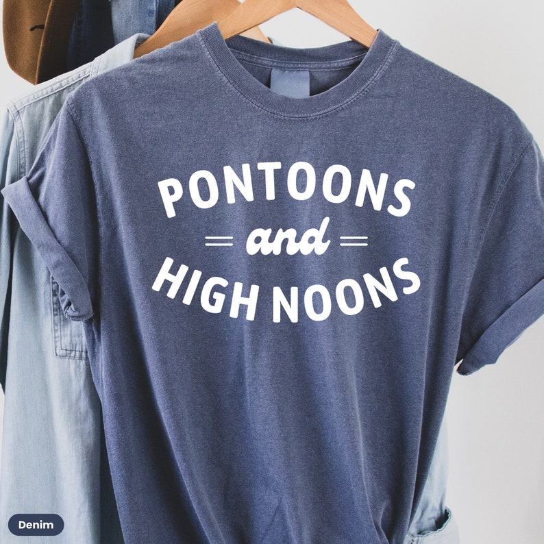 Pode incluir: Uma camiseta azul com texto branco que diz "Pontoons = and = High Noons".