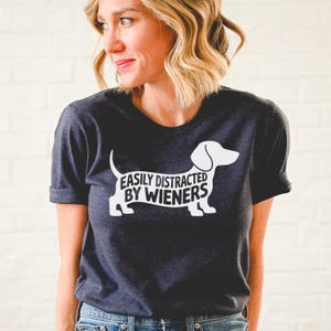 May include: A dark gray t-shirt with a white dachshund silhouette and the text "EASILY DISTRACTED BY WIENERS".