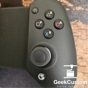 May include: Black gaming controller with a circular joystick, four face buttons, and a directional pad. The controller has a white logo with a stylized 3D printer icon and the text "GeekCustom CUSTOM 3D PRINTING".