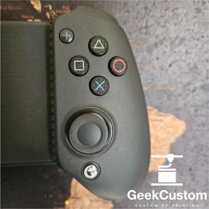 May include: A black gaming controller with coloured action buttons. The controller features a directional pad, analog stick, and a plus button. The text "GeekCustom" and "CUSTOM 3D PRINTING" are visible.