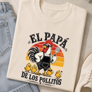 Peut inclure: Un t-shirt couleur crème avec une illustration d'un coq portant des lunettes de soleil et un tablier, tenant une spatule, entouré de quatre poussins. Le texte "EL PAPÁ DE LOS POLLITOS" est imprimé en noir au-dessus et en dessous du motif.
